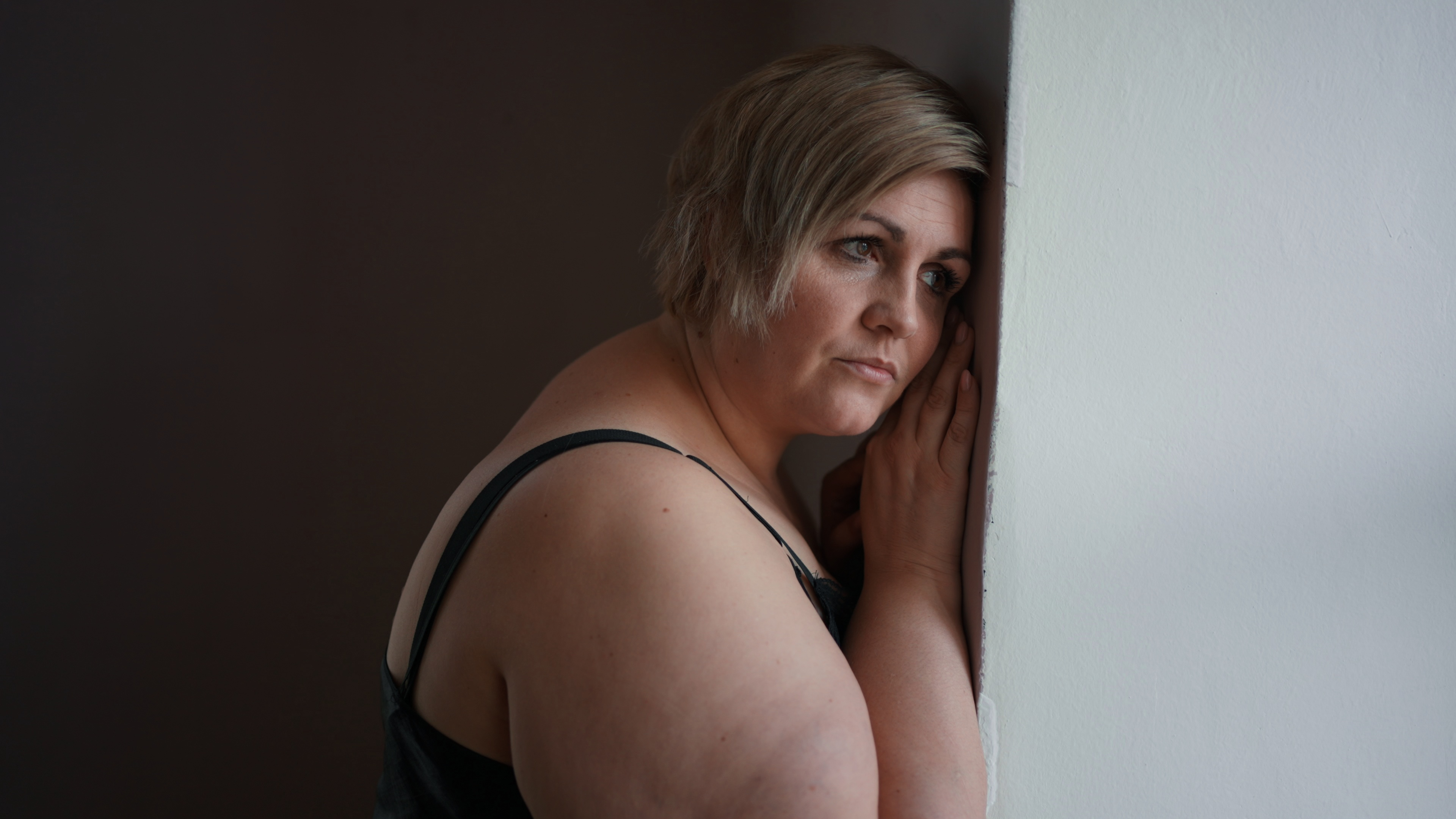 depressed lonely fat woman standing and leaning the wall at home and thinking SBI 351429213