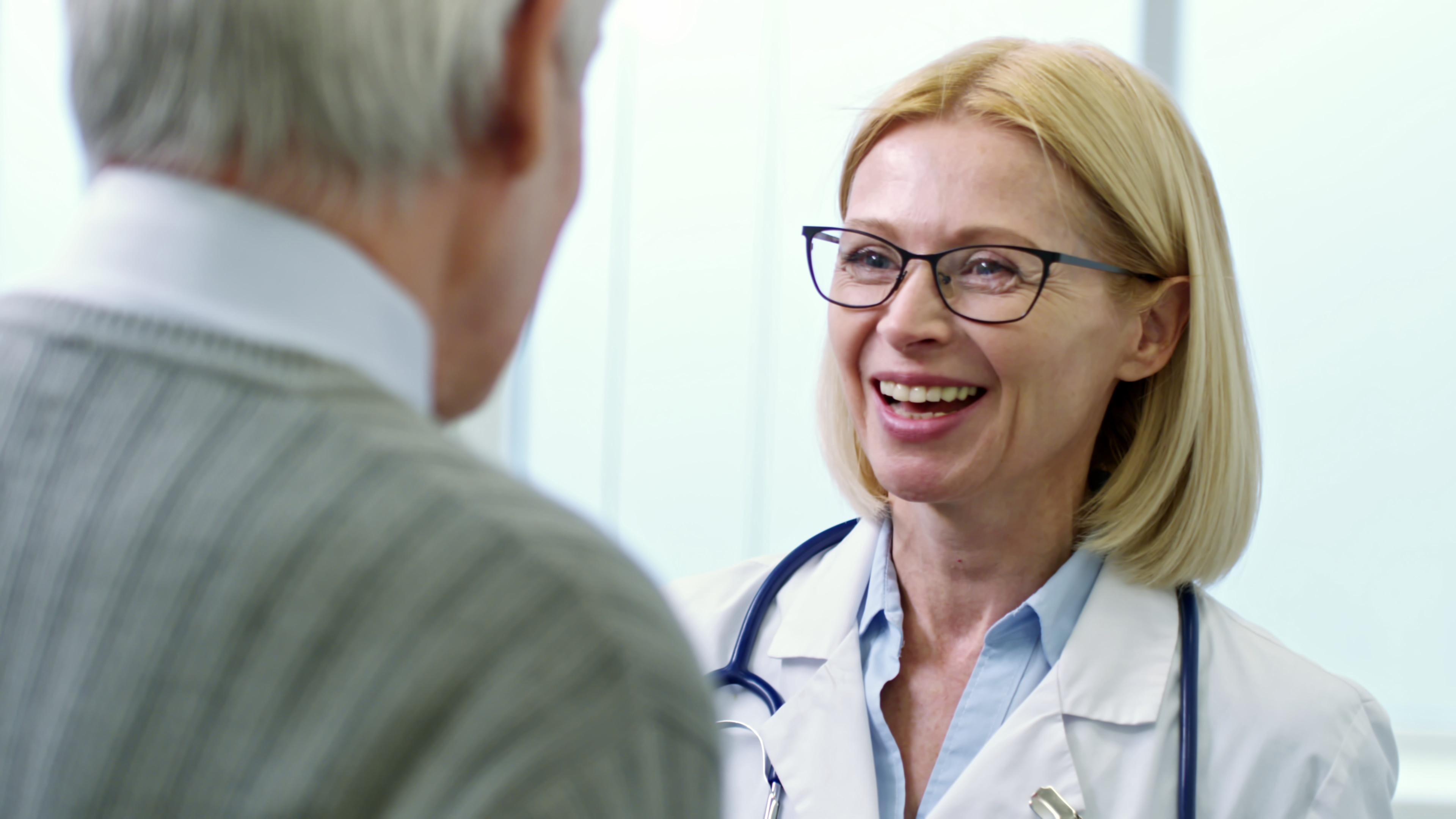 medium shot of cheerful female doctor in lab coat laughing and talking to senior patie SBI 350167424