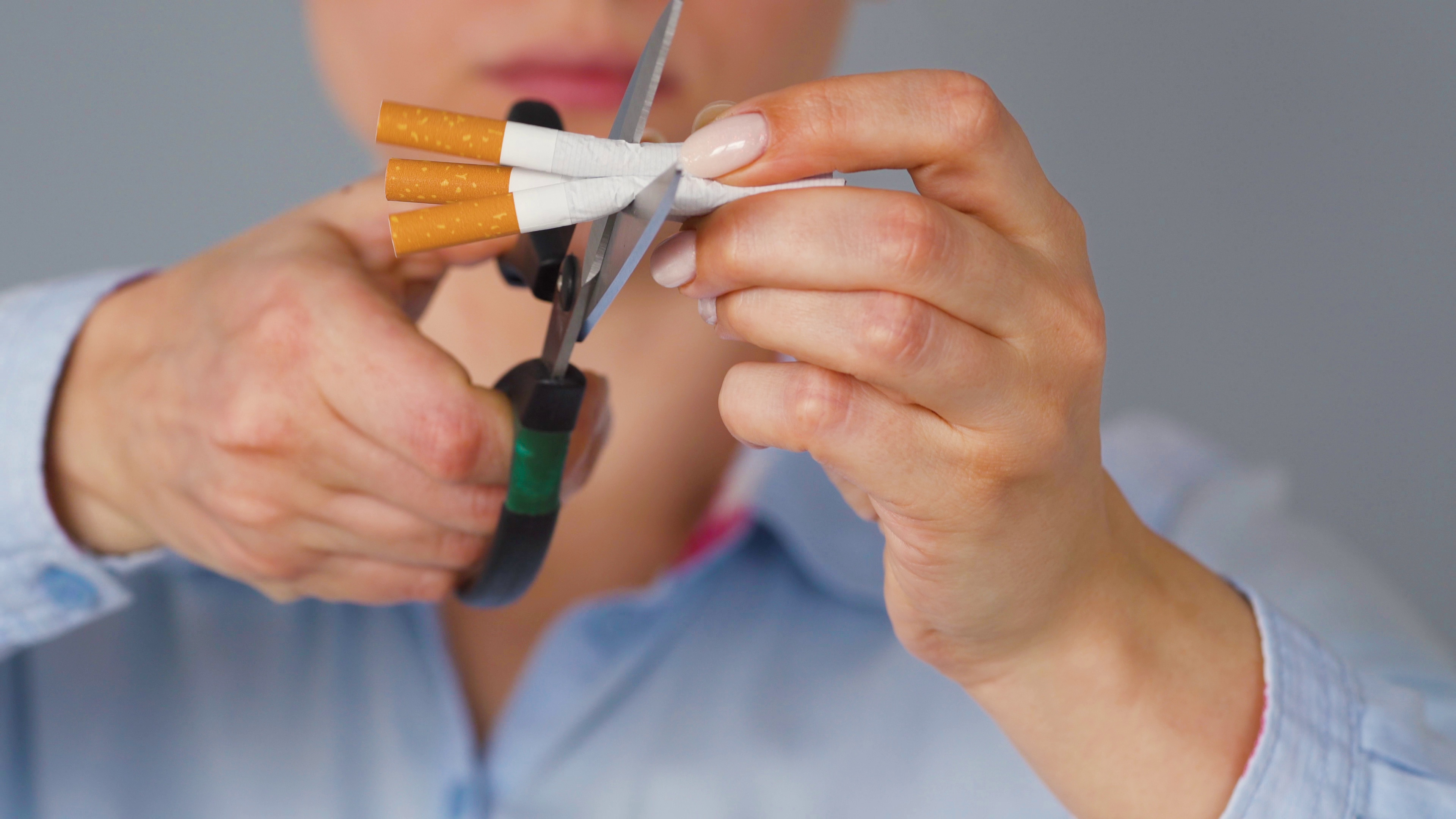 quit smoking concept woman cuts cigarettes with scissors SBI 350682264